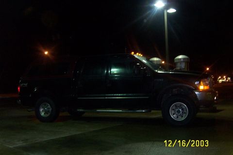 2000 Ford F-250 - Side view of a black 2000 Ford F-250 Super Duty pickup truck with a cap, parked outdoors at night.
