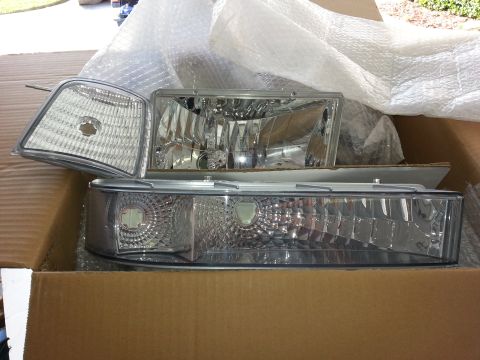 1994 Ford Bronco - Two headlights and a corner light are packaged in a cardboard box, ready for installation.