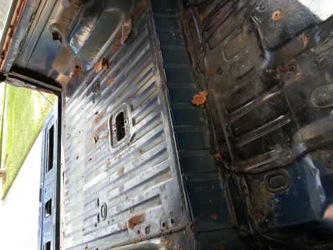 1994 Ford Bronco - The interior floor of a vehicle exhibits extensive rust and damage, revealing its underlying metal structure.