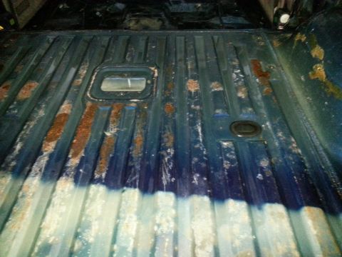 1994 Ford Bronco - The bed of a truck shows extensive rust damage and some white residue.