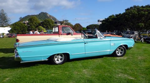 1964 Mercury Monterey - A classic blue convertible is parked on a grassy field, with a pickup truck and other vehicles in the background under a clear sky.