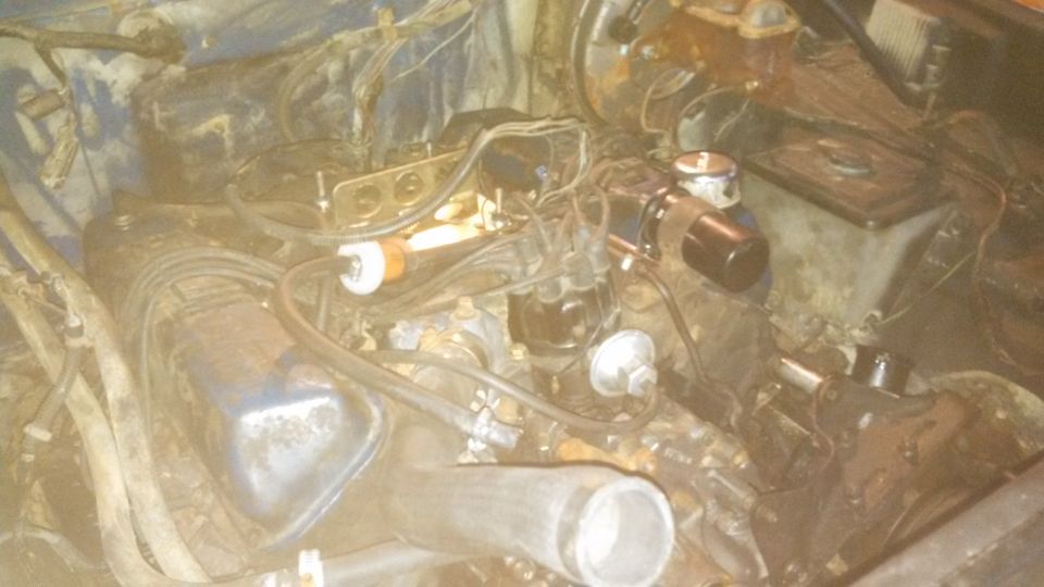 Engine bay with visible carburetor, distributor, and brake fluid reservoir