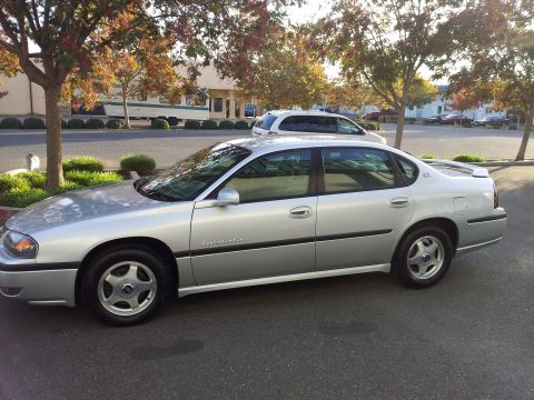 2001 Chevrolet Impala - A silver sedan is parked on asphalt with trees and buildings in the background.