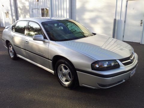 2001 Chevrolet Impala - Silver Chevrolet sedan parked in front of a corrugated metal building.