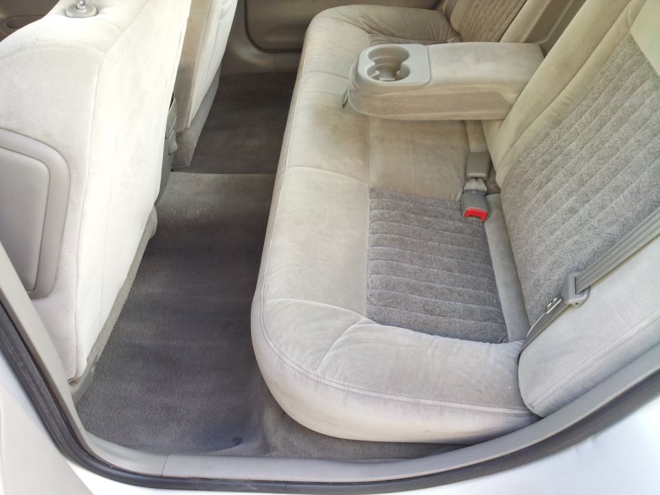 Gray cloth rear bench seat and floor of a sedan with center fold-down armrest