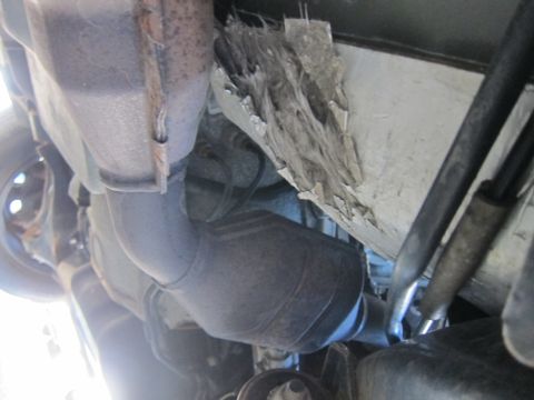 2001 Ford Crown Victoria - The undercarriage of a vehicle reveals its exhaust system and damaged heat shielding.