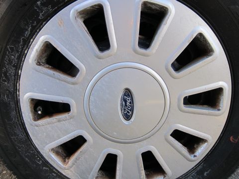 2001 Ford Crown Victoria - A close-up view of a Ford wheel, showing the brand's emblem on the hubcap and the tire's tread.