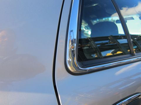 2001 Ford Crown Victoria - Close-up of the chrome trim and window frame on the rear passenger door of a silver vehicle.