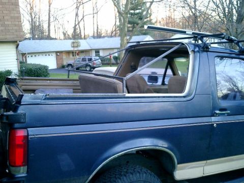 1990 Ford Bronco - The rear section of a blue Ford Bronco is visible, with a roof rack installed and the top removed.