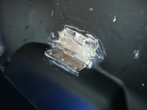 1994 Ford Bronco - A close-up view of a metal bracket secured with screws to a dark, possibly painted surface, indicating a repair or modification.