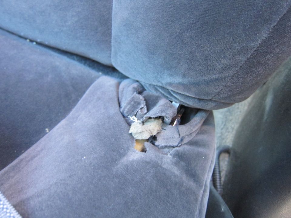 Torn blue car seat fabric showing foam padding underneath
