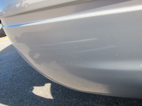 2001 Ford Crown Victoria - The rear bumper of a silver vehicle shows significant scuffing and scratches.