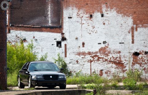 2003 Mercury Marauder - A black 2003 Mercury Marauder sits parked in front of an old brick building with peeling paint.