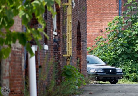 2003 Mercury Marauder - A black 2003 Mercury Marauder is partially obscured by foliage in a narrow alley.