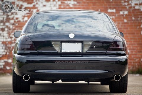 2003 Mercury Marauder - Rear view of a black 2003 Mercury Marauder sedan parked against a brick wall.