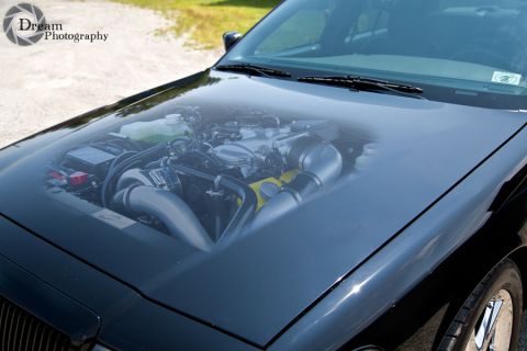 2003 Mercury Marauder - The hood of a black car features a realistic painting of an engine, giving the illusion of an exposed powerplant.