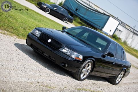 2003 Mercury Marauder - A black 2003 Mercury Marauder is parked on a gravel surface with another black car in the background.