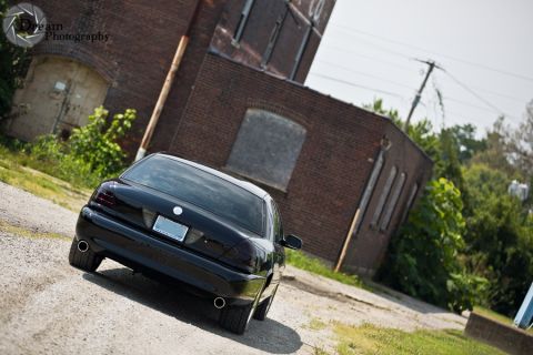 2003 Mercury Marauder - Rear view of a black sedan with tinted taillights parked in front of an old brick building.