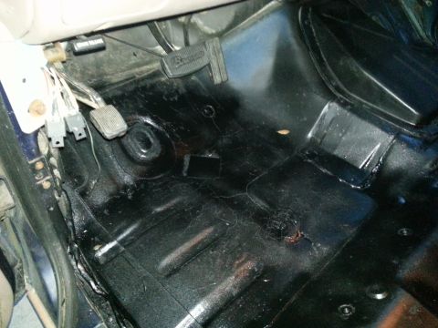 1994 Ford Bronco - The interior floor of a vehicle shows pedals and wiring, with a watermark indicating "SUPERMOTORS".