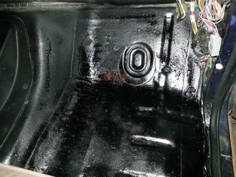 1994 Ford Bronco - The interior floor of a vehicle, showing the undercoating and some wiring harness components.