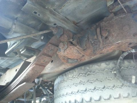 1994 Ford F-250 - The underside of a truck shows significant rust on the leaf springs and frame, with a spare tire visible.
