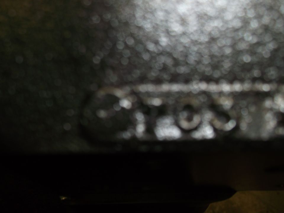 Blurry close-up of raised cast lettering on a dark metal vehicle part