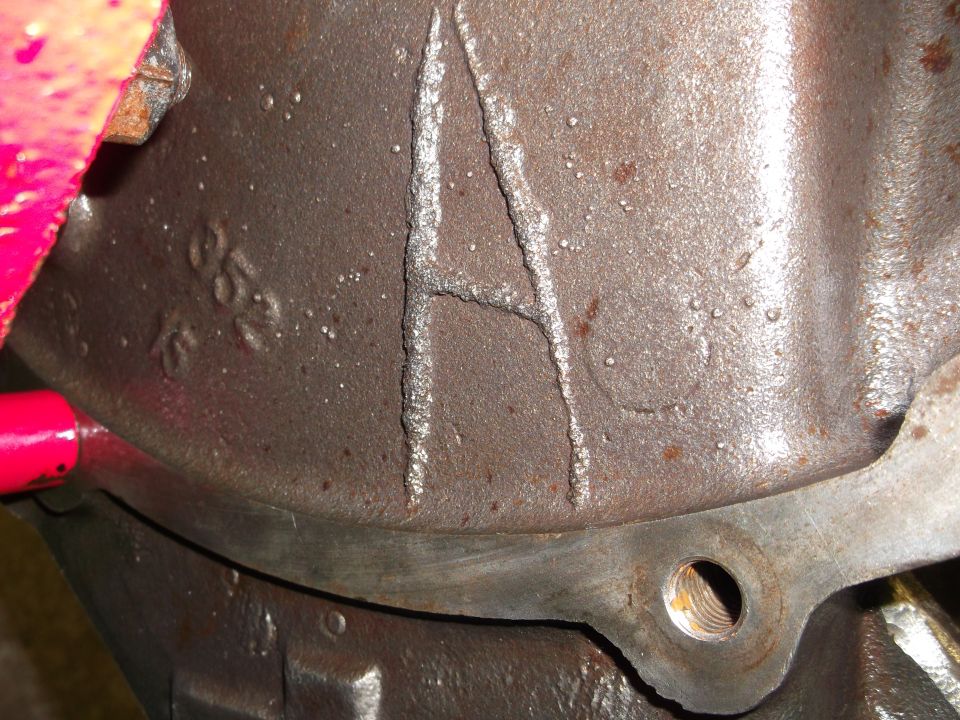 Close-up of a cast metal engine part with a large letter A and some numbers stamped on it