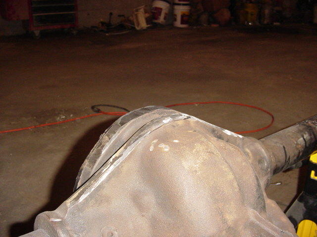 Dusty solid rear axle housing with differential lying on a garage floor