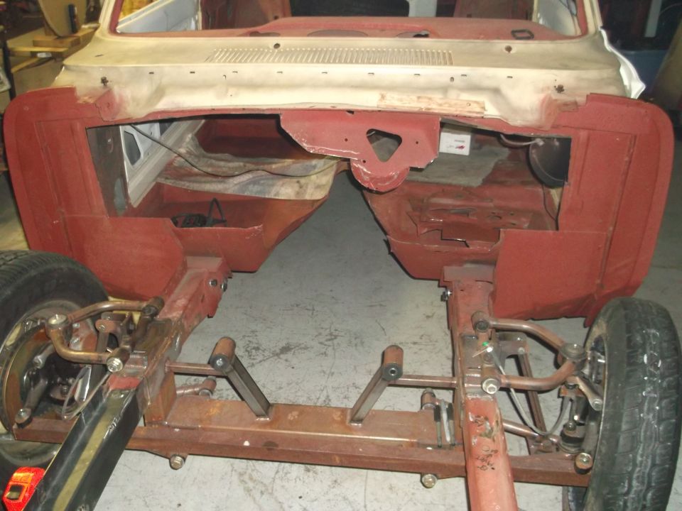 car body shell on stands, showing chassis and suspension components