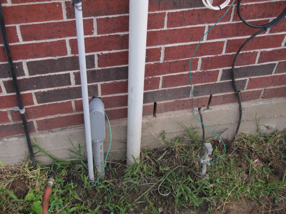 electrical conduit, grounding rod, and wires near brick wall