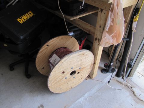 1995 Ford Bronco - Two large wooden spools, one with wire, sit on a concrete floor next to a workbench.