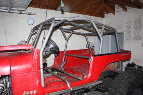 1985 Jeep CJ7 - This red Jeep CJ features a custom roll cage and appears to be undergoing modifications.