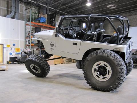 1985 Jeep CJ7 - Modified Jeep Wrangler with roll cage and large off-road tires, showing Rubicon badging.