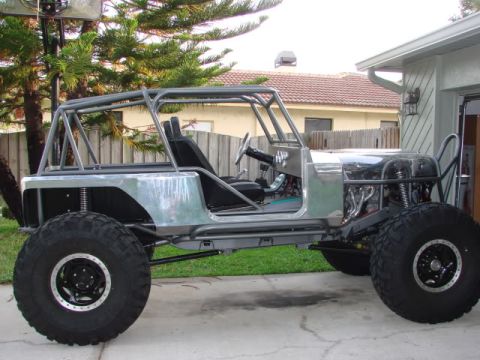 1985 Jeep CJ7 - This custom off-road vehicle has a roll cage and large tires, with its engine partially exposed.
