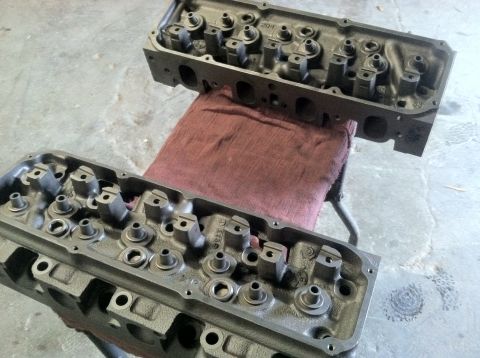 1978 Ford Bronco - Pair of engine cylinder heads, likely from a V8 engine, are shown on a workbench.
