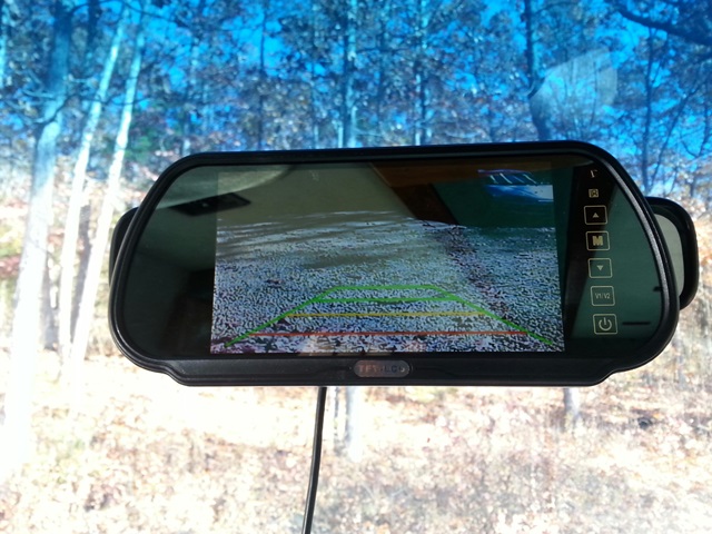 Rear-view mirror displaying a grainy backup camera feed with colored guide lines