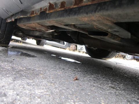 2001 Ford Crown Victoria - Undercarriage of a vehicle with visible rust on the frame and suspension parts.