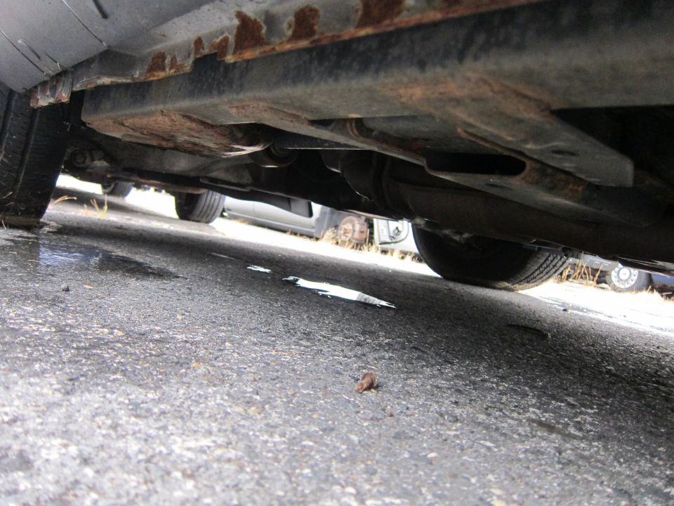 Underside view of a car showing rusty frame rails and suspension components