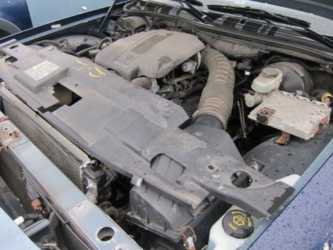 2001 Ford Crown Victoria - The engine bay of a 2001 Ford Crown Victoria is visible, with the hood open and various mechanical parts exposed.