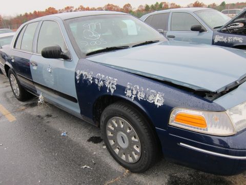 2001 Ford Crown Victoria - Two police cars are parked outside, one with "STATE POLICE" text visible on the fender.
