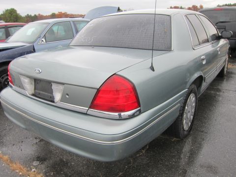 2001 Ford Crown Victoria - A gray 2001 Ford Crown Victoria is parked in a lot with other vehicles under an overcast sky.