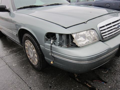 2001 Ford Crown Victoria - Front passenger side of a 2001 Ford Crown Victoria shows damage to the headlight and fender area.