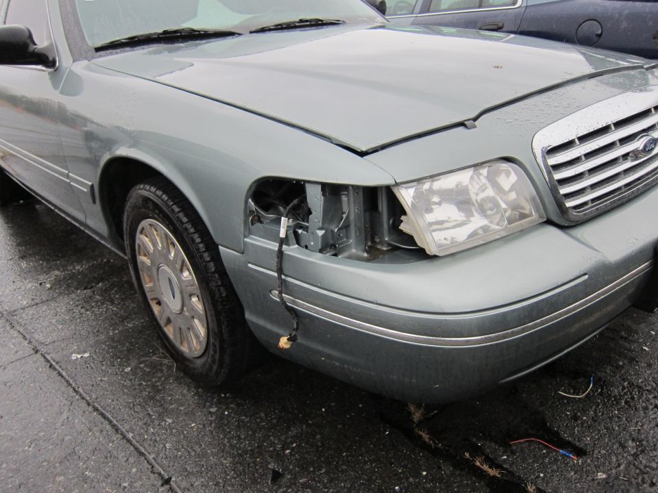 2001 Ford Crown Victoria with missing headlight assembly and damaged fender