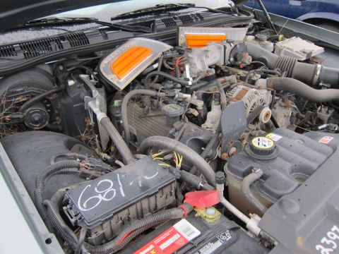 2001 Ford Crown Victoria - The engine bay of a vehicle, showing the fuse box, battery, and various engine components. Text on the fuse box reads '681-72'.