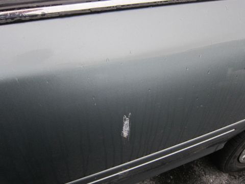 2001 Ford Crown Victoria - A close-up view of damage on the side of a vehicle, showing a significant scratch.
