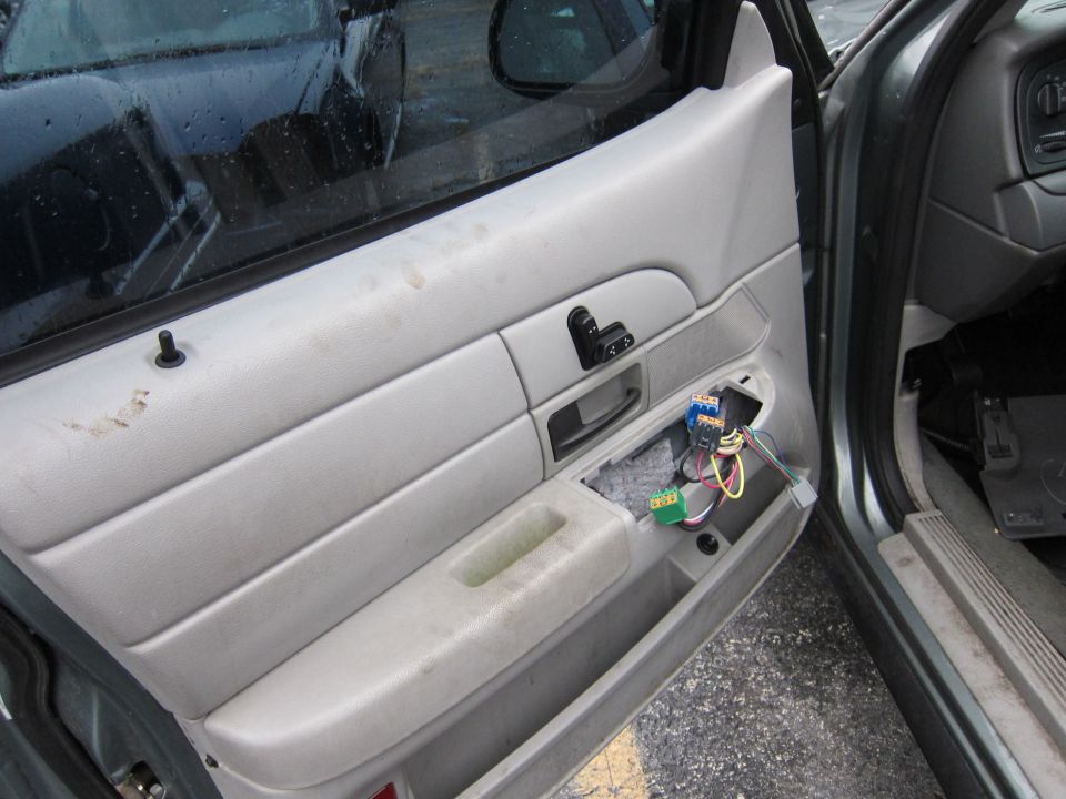 Car interior door panel with exposed wiring and window controls