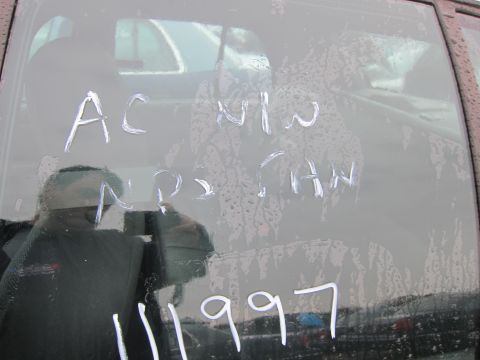 2001 Ford Crown Victoria - Writing on a car window shows "AC NW NPS CHW 11 1997" with reflections and water droplets.