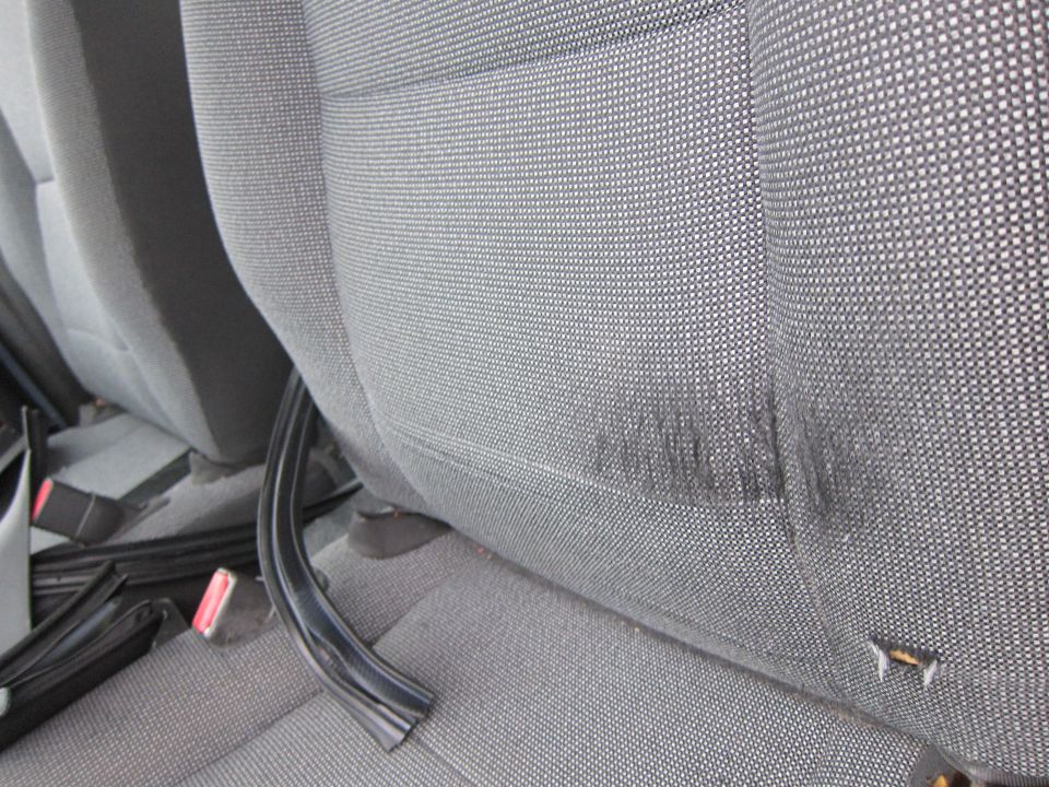 Close-up of gray fabric car seats with a black trim piece on the floor