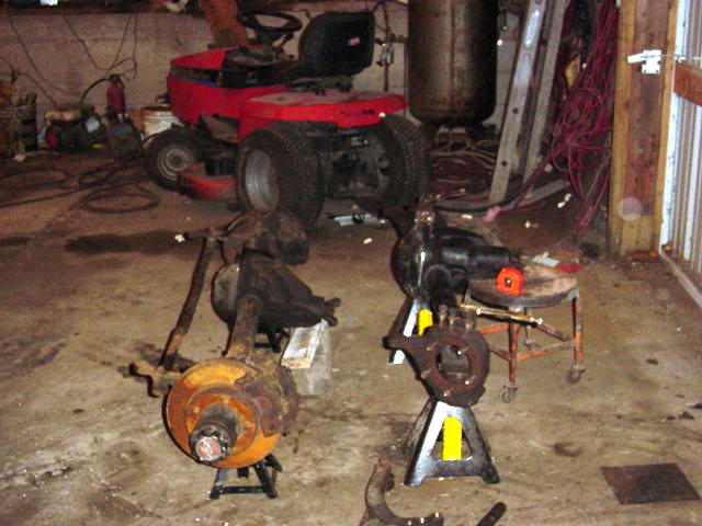 Two front axle assemblies on jack stands in a garage