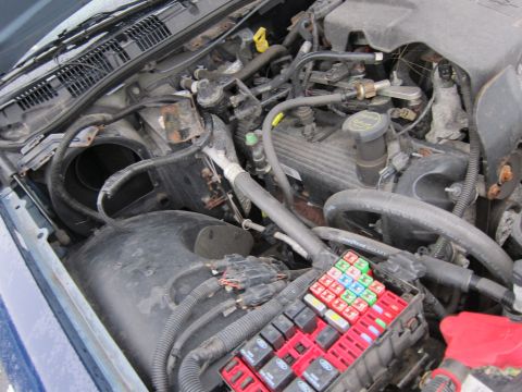 2001 Ford Crown Victoria - The engine bay of a 2001 Ford Crown Victoria, a prominent fuse box and various engine components.